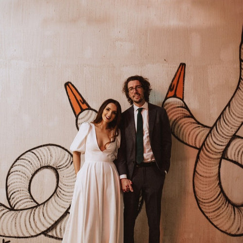 Wedding couple smiling in front of artistic wall decor in Chicago, their Glamour Girl Airbrush Tans adding to their wedding glow.