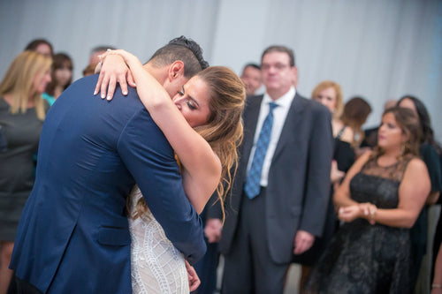 Groom embracing bride at wedding reception, makeup by Glamour Girl