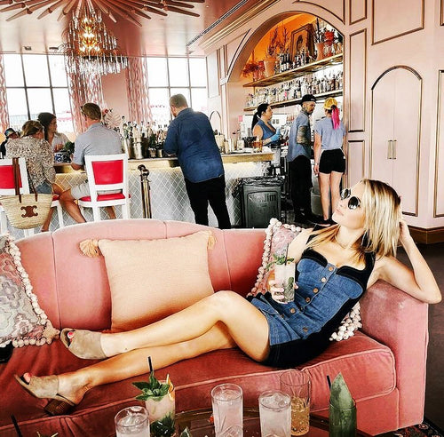 Woman lounging in a stylish Chicago bar, her spray tan by Glamour Girl Airbrush Tan adding to her relaxed vibe.